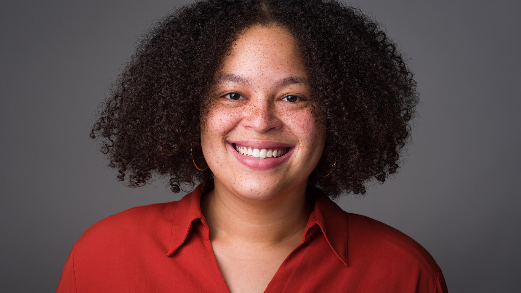 Professional Headshot Headshot for young professional black woman smiling afro freckles red blouse by Tampa photographer Sidney Oster