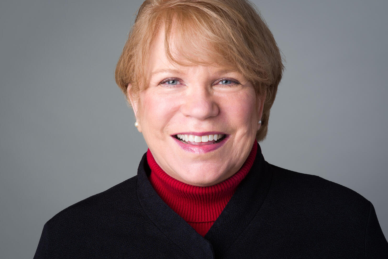 Executive Headshot Professional headshot of smiling mature woman executive black coat red turtleneck by Tampa photographer Sidney Oster