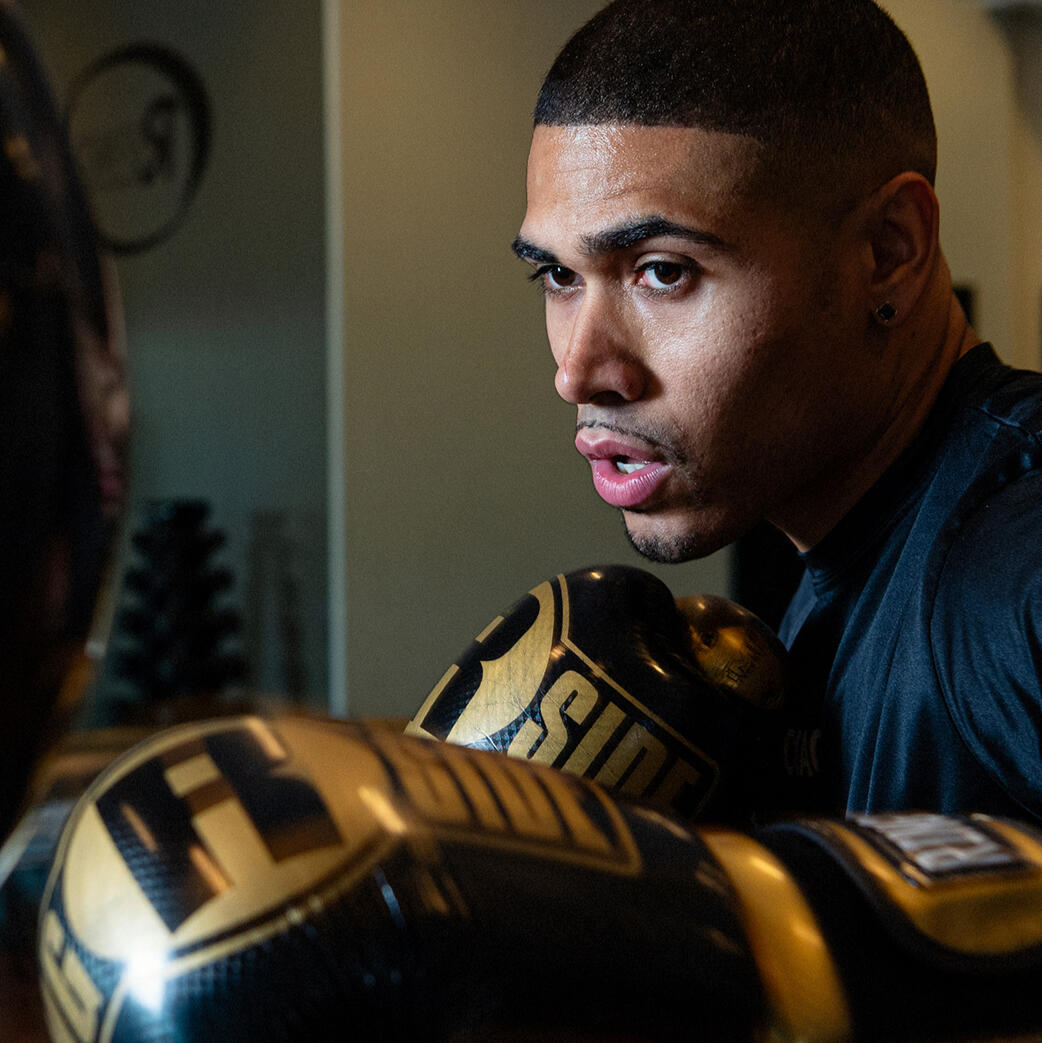 Young black man wearing boxing gloves hitting a punching ball